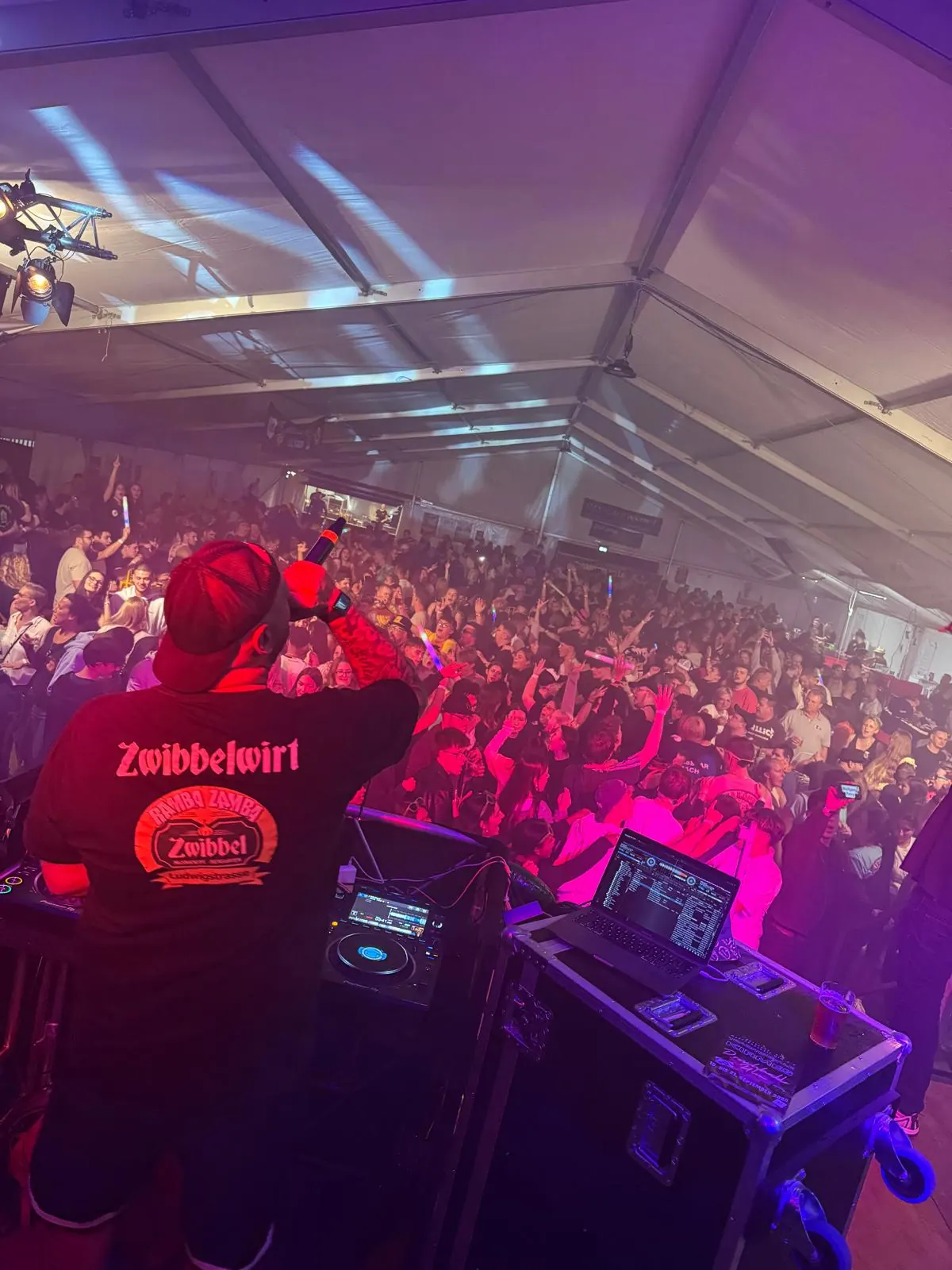 Blick von der Bühne über das DJ-Pult in die tanzende Menge